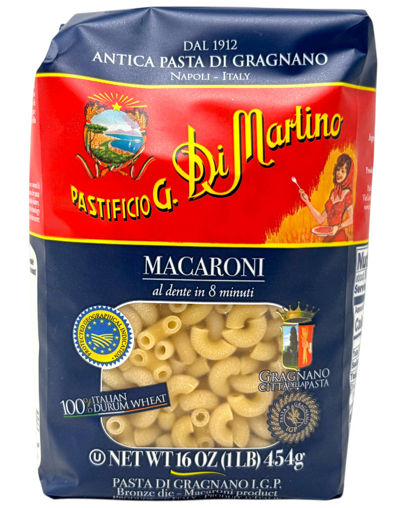 A 16 oz bag of Di Martino Macaroni pasta, featuring the brand's classic red and navy blue packaging with a clear window showing the elbow macaroni inside.